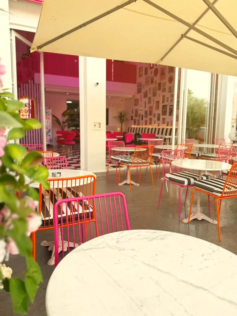 La terrasse et ses chaises roses et orange autour de tables en marbre